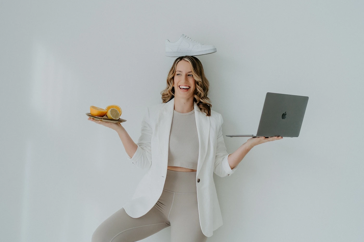 Freu beim Personal Brand Fotograf – mit Laptop, Sneaker auf dem Kopf und Orangen in der Hand - Coach für Hormone